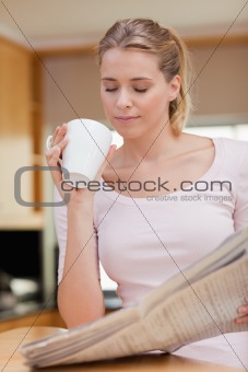 Portrait of a cute woman reading the news while having tea