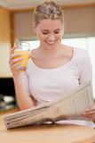 Portrait of a woman reading the news while drinking orange juice