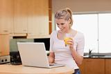 Woman using a laptop while drinking juice
