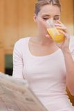 Portrait of a beautiful woman reading the news while drinking juice