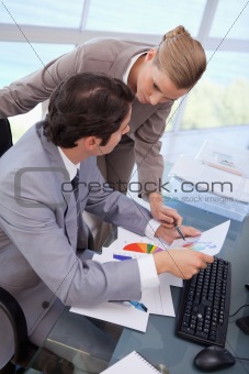 Portrait of a manager pointing at something to her secretary on a graph