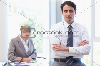 Businessman posing while his colleague is working