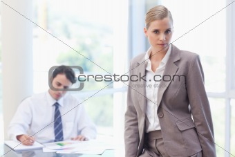 Businesswoman posing while her colleague is working