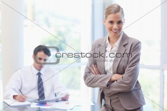 Smiling businesswoman posing while her colleague is working