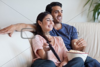 Couple watching TV while eating popcorn
