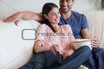 Delighted couple watching TV while eating popcorn