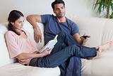Woman reading a book while her fiance is watching TV