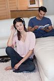 Portrait of a woman listening to music while her fiance is reading a book