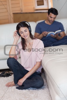 Portrait of a woman listening to music while her fiance is reading a book