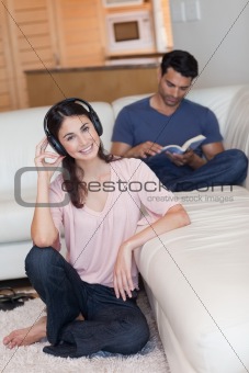 Portrait of a young woman listening to music while her fiance is reading a book