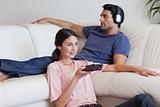 Woman watching TV while her fiance is listening to music