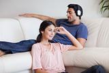 Woman watching TV while her husband is listening to music