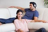 Young woman posing while her husband is listening to music