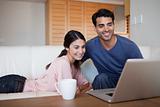 Young couple using a laptop while having a tea