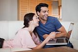 Laughing young couple using a laptop