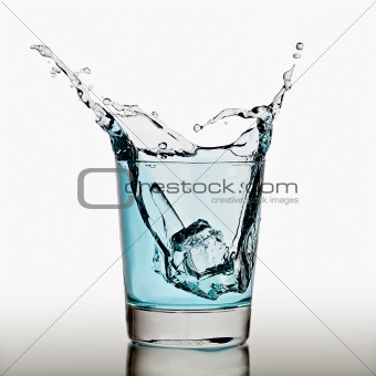 Ice cube splashing in a cool glass of water