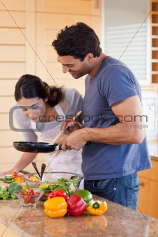 Portrait of a young couple cooking with a pan