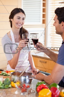 Portrait of a young couple having a glass of wine while cooking