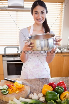 Portrait of a woman showing a sauce pan