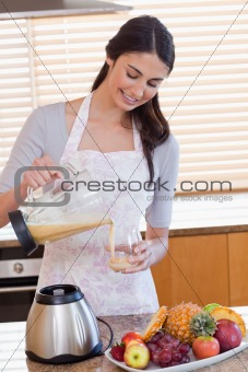 Portrait of a woman pouring fresh juice in a glass
