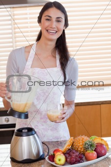 Portrait of a young woman pouring fresh juice in a glass