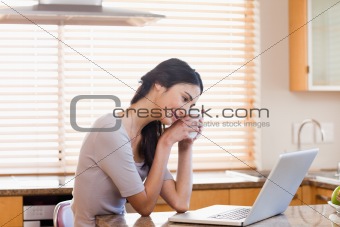 Lovely woman using a laptop while drinking a cup of a tea