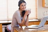 Charming woman using a laptop while drinking a cup of a coffee