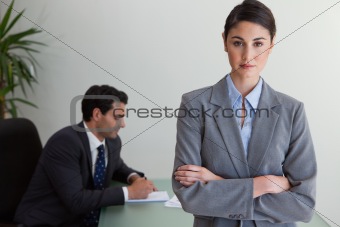 Professional businesswoman posing while her colleague is working