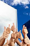 people's hand with thumbs up in front of modern building