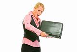 Unhappy modern business woman shaking out something from briefcase
