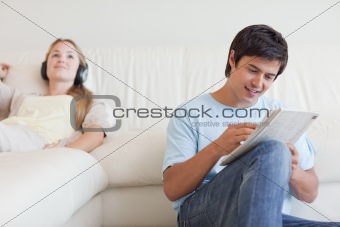 Man doing crosswords while his fiance is listening to music