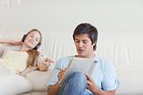 Woman helping her fiance to do crosswords while listening to music