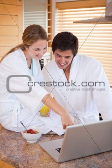 Portrait of a lovely couple having breakfast while using a laptop