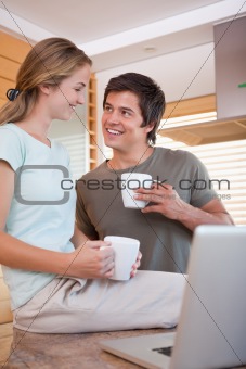 Portrait of a young couple having coffee while using a notebook