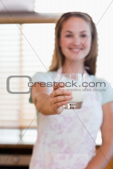 Portrait of a woman giving a glass of milk