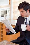Portrait of a businessman drinking tea while reading the news