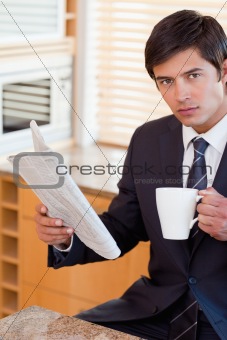Portrait of a businessman drinking tea while reading a newspaper