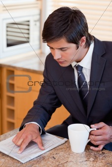 Portrait of a businessman drinking coffee while reading a newspaper