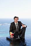 Portrait of a businessman posing with a cocktail on a briefcase