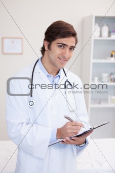 Smiling male doctor taking notes