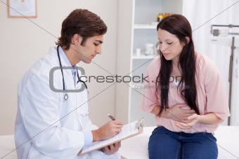 Male doctor writing down patients symptoms