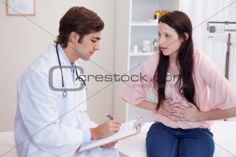 Male doctor writing down female patients symptoms
