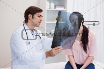 Doctor analyzing x-ray with his patient