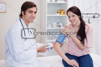 Smiling doctor taking patients blood pressure