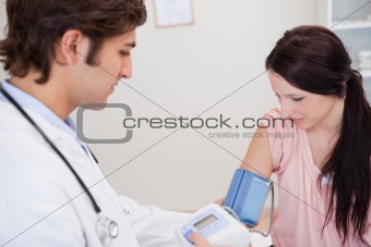 Male doctor taking female patients blood pressure