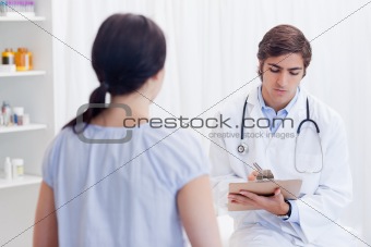 Physician taking notes while patient is talking