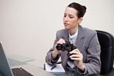 Businesswoman with binoculars on her desk