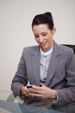 Smiling businesswoman sitting behind desk writing a textmessage