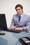 Smiling businessman typing on his keyboard