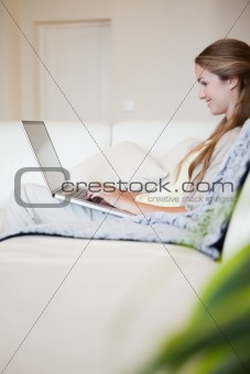 Side view of woman with her laptop sitting on the sofa